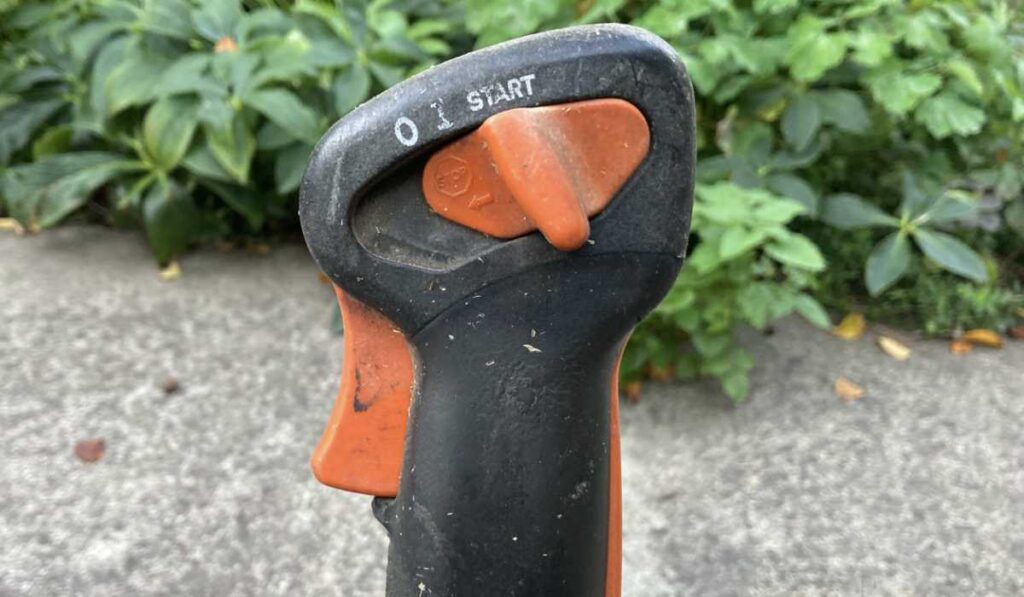 Stihl FS 200 bike handle controls showing the ignition switch and throttle lock settings.