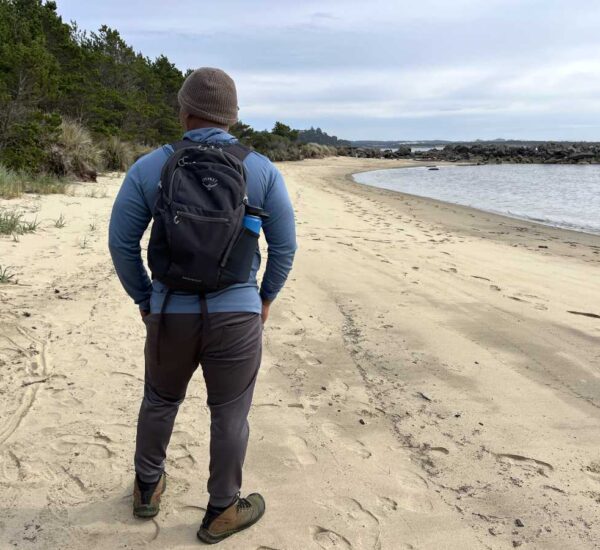 Earl Gibson reviewing the Osprey Daylite Plus backpack on a driftwood-covered beach at Heceta, Oregon.