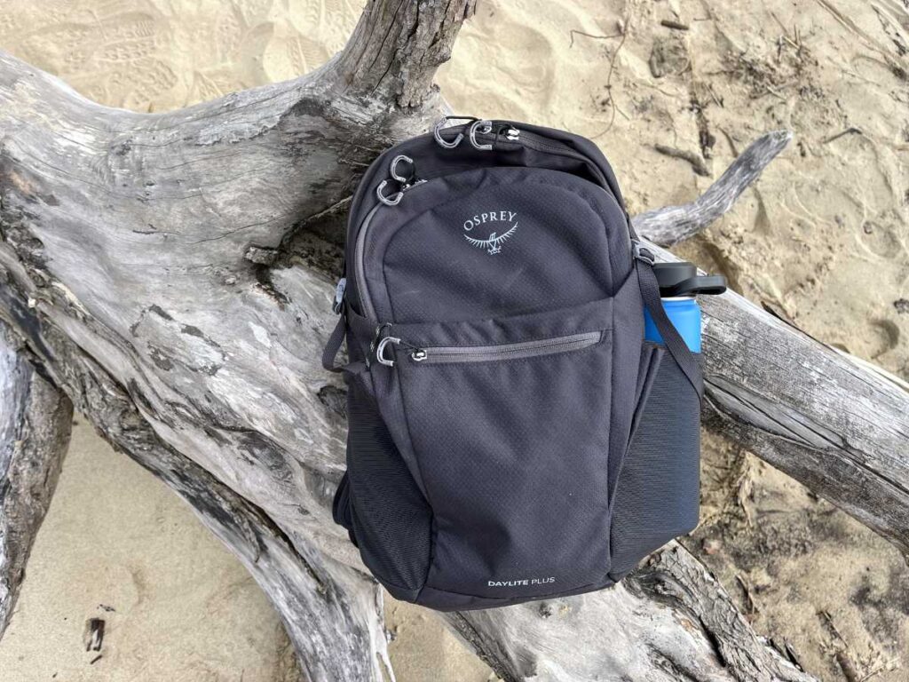 Osprey Daylite Plus 20L backpack sitting on driftwood at the Oregon coast during a field test.